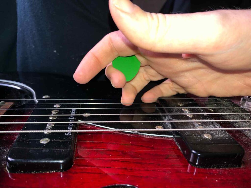 holding a guitar pick while fingerpicking